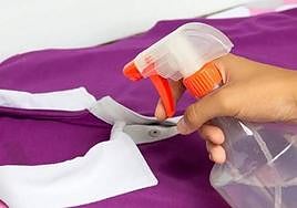 Una persona pulveriza un líquido sobre una prenda de ropa.