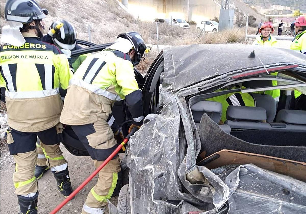 Los bomberos tratan de liberar al conductor.