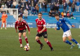 Pedro León, jugador del Real Murcia, juega el balón ante la mirada de su compñaero Enol Coto.