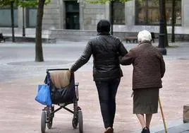 Una mujer ayuda a caminar a una anciana dependiente en una imagen de archivo.