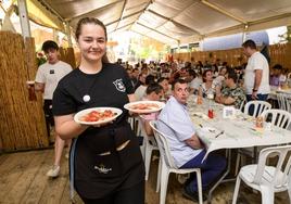 Una camarera de una barraca sostiene dos platos de ensalada murciana, en las Fiestas de Primavera de Murcia 2023.