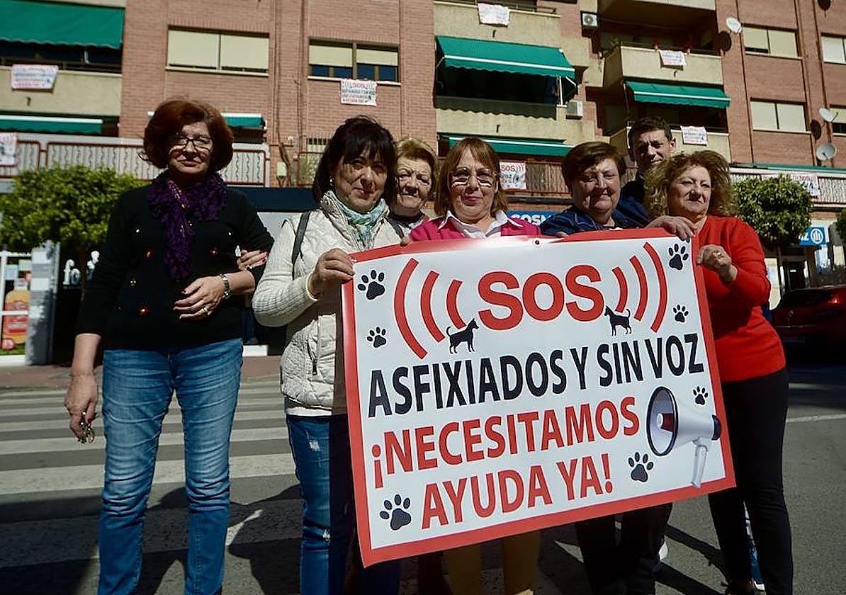 Vecinos con uno de los carteles que denuncian la insalubridad con la que conviven en un bloque de viviendas de Beniaján.