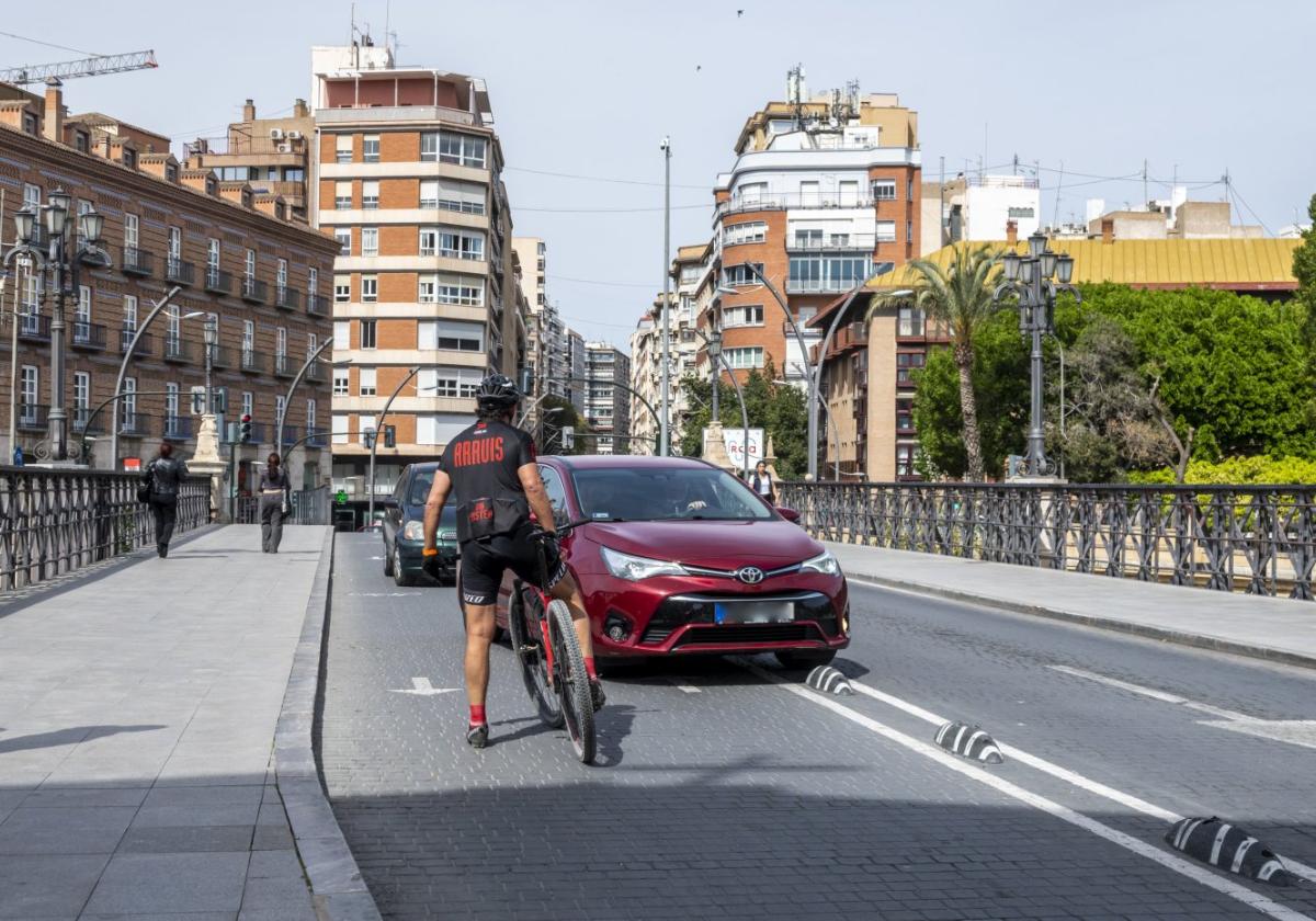 Un ciclista pide explicaciones, ayer, a dos conductores tras invadir estos el carril bici sobre el Puente Viejo.