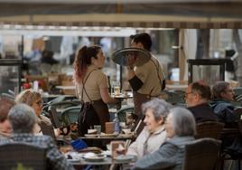 Dos camareros hablan entre ellos en la terraza de un bar de la plaza Belluga, en Murcia.