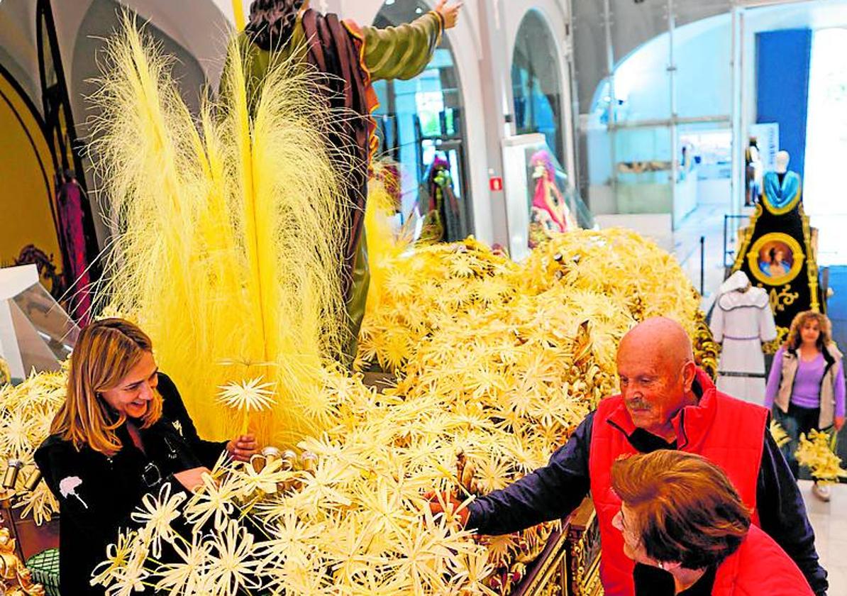 Cofrades blancos colocan las flores de palma en el trono.