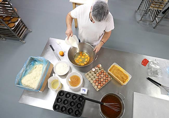 Juanra Martínez vierte la leche en el recipiente donde inicia la elaboración del bizcocho en el obrador.