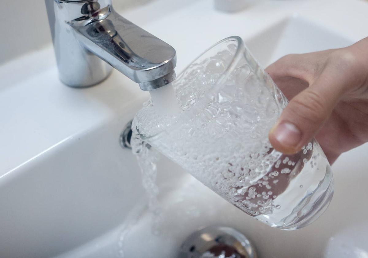 Un consumidor llena un vaso con agua del grifo.