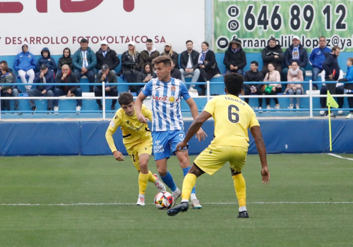 El aguileño Góngora intenta irse del marcajo de dos jugadores del Cartagena B, ayer.