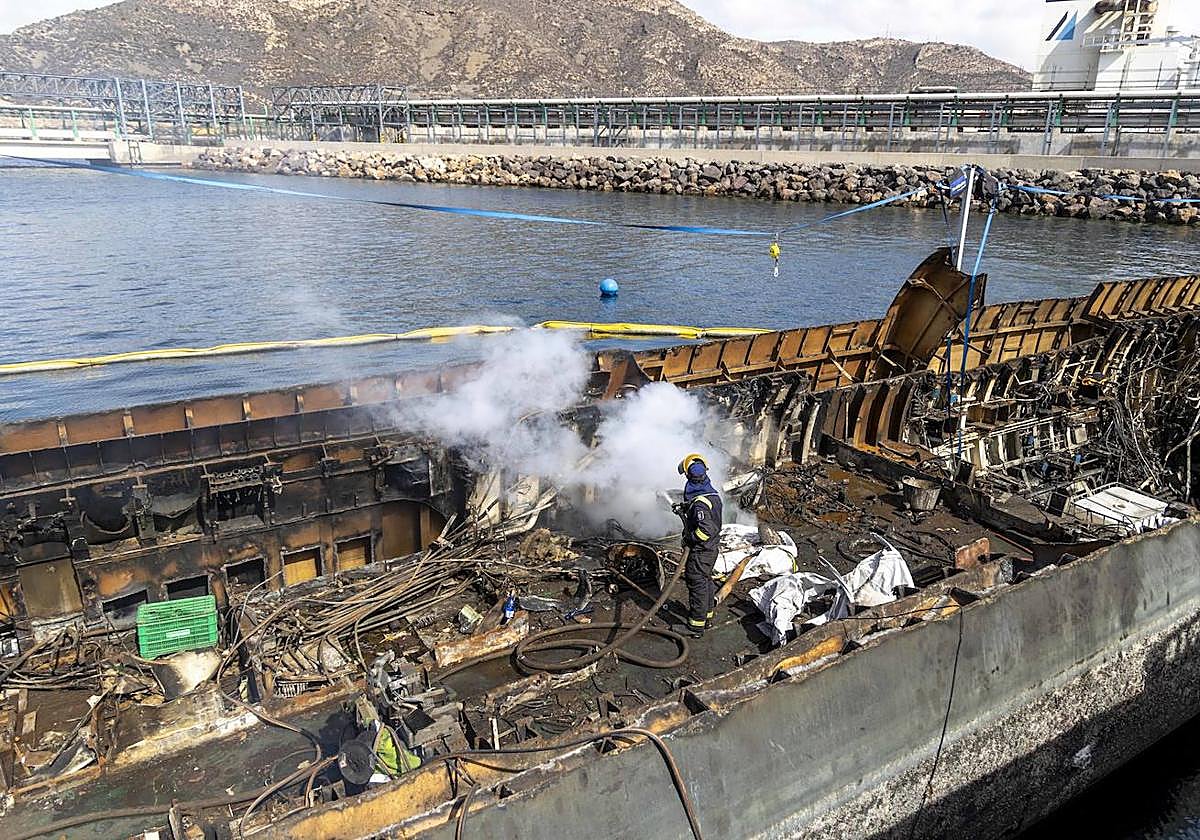 Un operario de la empresa Hermanos Inglés enfría con agua una de las zonas del submarino 'Mistral' cortadas por un compañero con soplete, en un muelle de Escombreras.