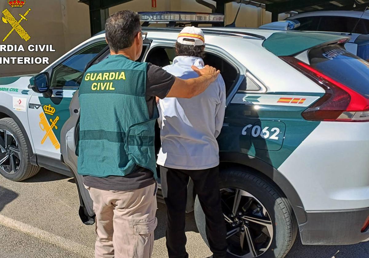 Un agente introduce a uno de los detenidos en el coche patrulla.