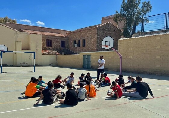 Los niños reciben las instrucciones del monitor en la pista del colegio.