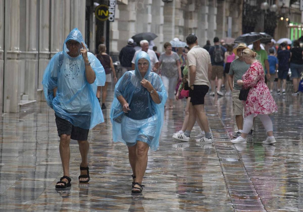 Unas personas se cubren con un chubasquero en un día de lluvia en Cartagena.