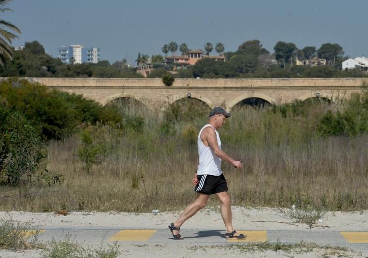 Un bañista pasea sobre los restos de la antigua carretera en Campoamor el mes pasado.