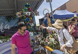 Una mujer toca la mano de la Dolorosa, con la cruz de mayo de fondo.