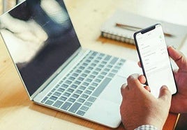 Una persona conectada a internet desde su portátil y desde su móvil. Imagen de archivo.