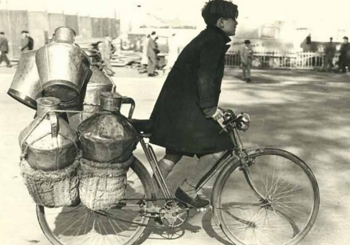Transporte. Un muchacho acarrea una bicicleta cargada de lecheras camino de las expendedurías.