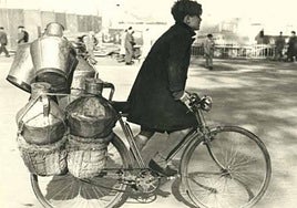 Transporte. Un muchacho acarrea una bicicleta cargada de lecheras camino de las expendedurías.