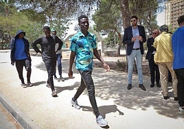 Un grupo de inmigrantes acogidos en el Naval pasa por delante del líder regional de Vox, José Ángel Antelo.