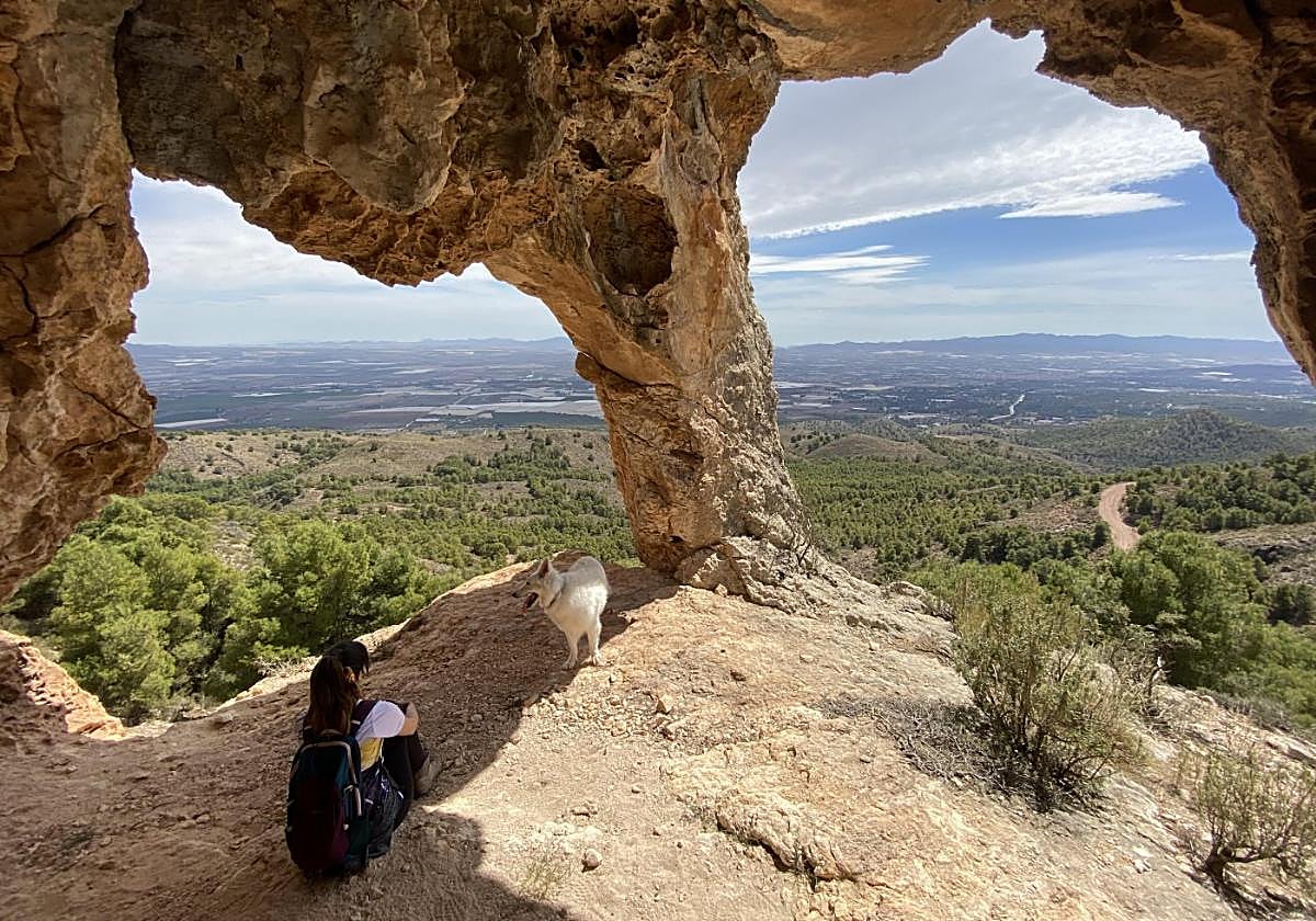 Una senderista observa el paisaje bajo la formación geológica Los ojos del dragón, en el parque regional de Sierra Espuña.