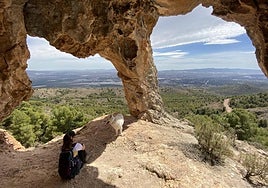 Una senderista observa el paisaje bajo la formación geológica Los ojos del dragón, en el parque regional de Sierra Espuña.