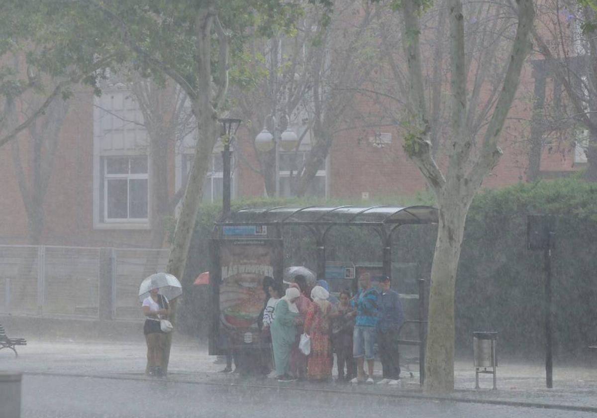 Varias personas se resguardan de la lluvia en Cartagena bajo una parada de bus.