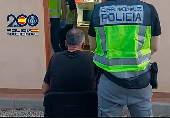 Un agente custodia a uno de los arrestados en Murcia.