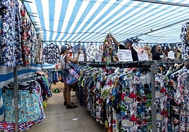 Varias personas echan un vistazo a la ropa de uno de los puestos del mercadillo de venta ambulante de Cabo de Palos este domingo.