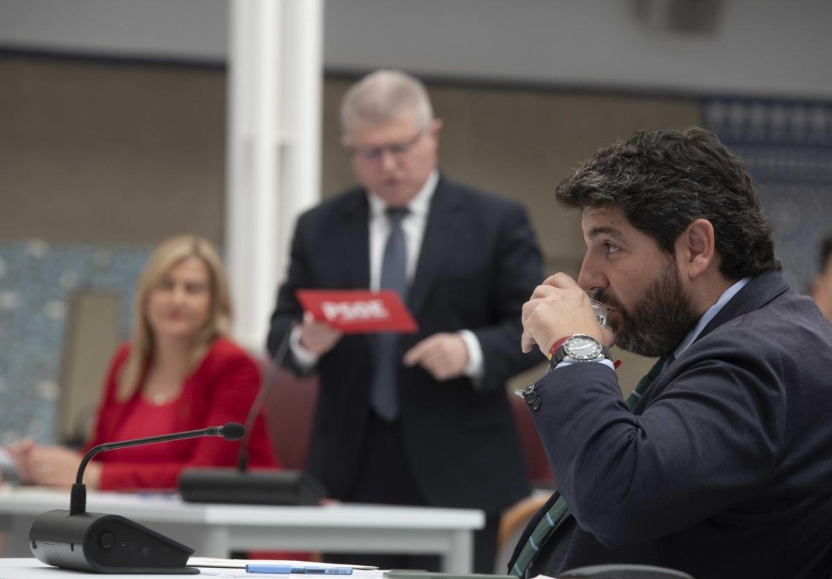 López Miras bebe agua mientras interviene el socialista José Vélez en la Asamblea.