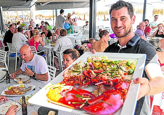 Un camarero sirve un plato a unos clientes sentados en la terraza de un restaurante de La Manga.