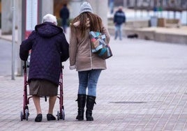 Una anciana dependiente pasea acompañada de una cuidadora.