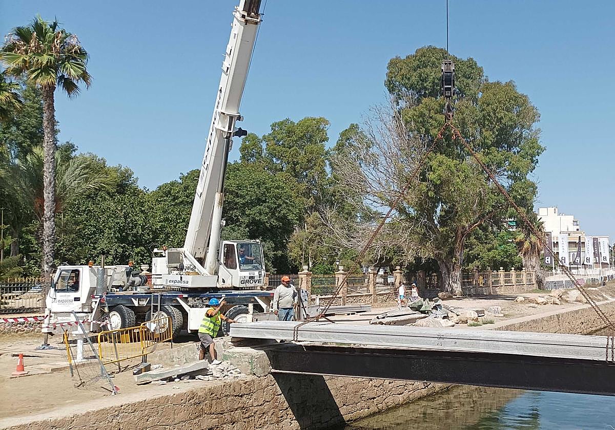 Operarios trabajando en la reparación del puente peatonal sobre el canal del Acequión.