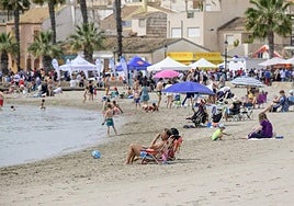 Vecinos y visitantes, tomando el sol en una playa de Los Alcázares.