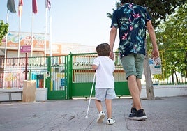 Diego, ciego de nacimiento, camina de la mano de su padre y con su bastón.