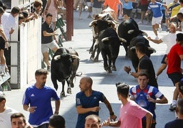 Varios jóvenes corren delante de los novillos en el tercer encierro de las fiestas de Blanca.