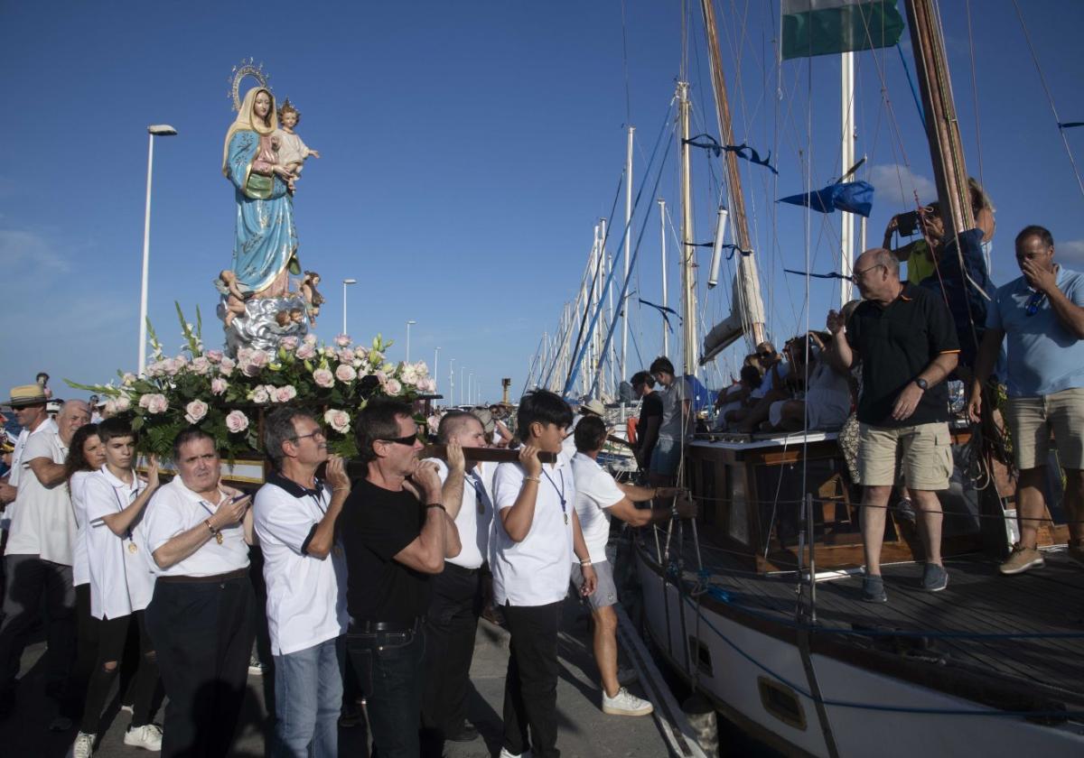 La imagen de la Virgen, a hombros, en el momento de subirla a la embarcación en Los Nietos, en la tarde de ayer.