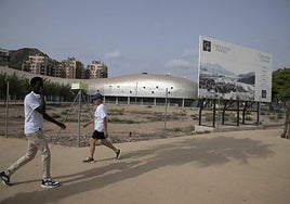 Dos hombres pasan junto al solar donde debería estar ya el primer bloque de edificios del Plan Rambla, promovido por el conocido empresario cartagenero Tomás Olivo.