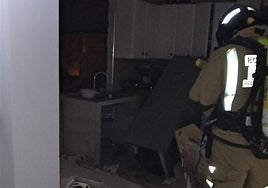 Un bombero trabaja en el interior de la vivienda donde estalló la bombona de butano.