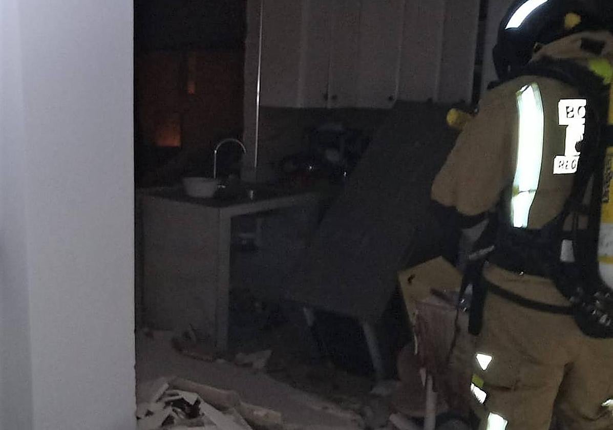 Un bombero trabaja en el interior de la vivienda donde estalló la bombona de butano.