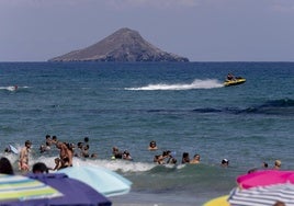 Una moto de agua circula al otro lado de las boyas en una playa de La Manga.