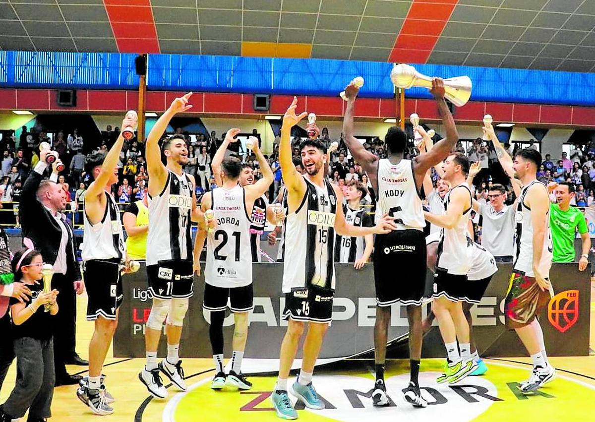 Imagen secundaria 1 - Plantilla y directivos del Odilo FC Cartagena celebran el ascenso a LEB Oro en Zamora, el pasado 22 de abril, y la polaca Rembiszewska, con el balón, en un partido del pasado 'playoff', contra el Girona.