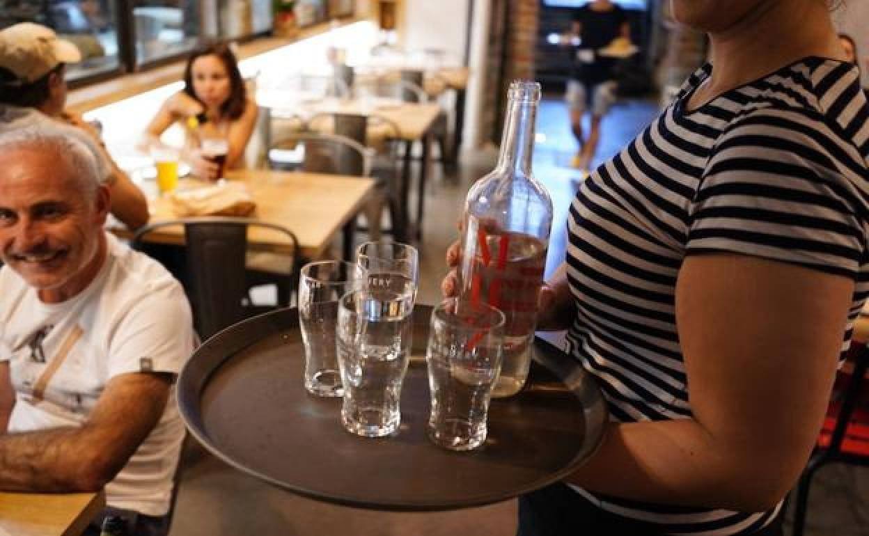 Una camarera sirve agua a unos clientes.