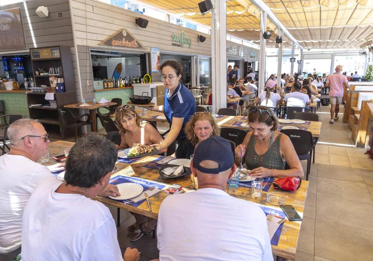 Una camarera atiende a unos clientes en la terraza de un restaurante de La Manga.