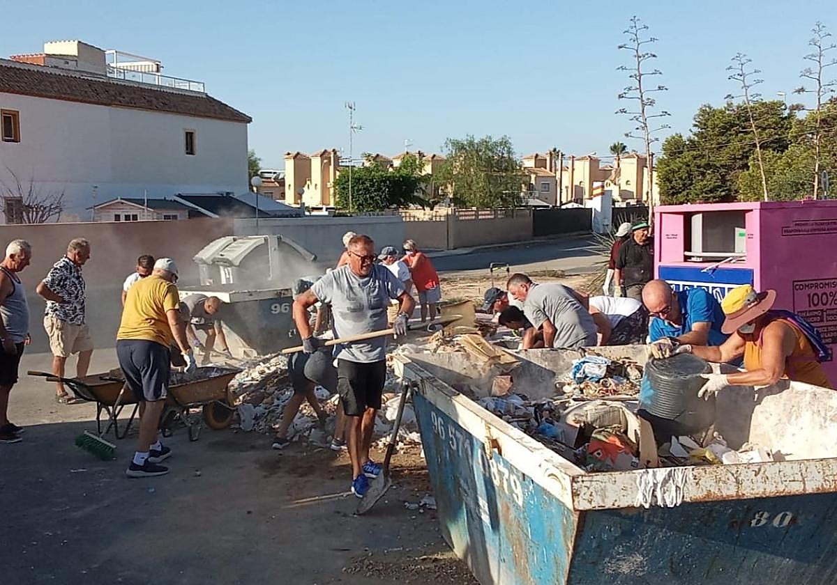 Vecinos depositan los escombros en un contenedor.