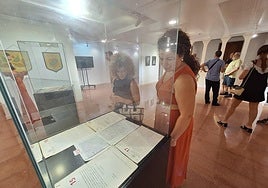 La concejal de Festividades, Rocío Ortuño (izquierda), observa el acta fundacional de las fiestas en un vitrina instalada en el Museo de la Reconquista.