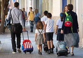 Imagen de archivo de unos padres llevando a sus hijos al colegio.