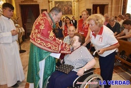 El sacerdote ofrece la Cruz para su adoración a una feligresa.