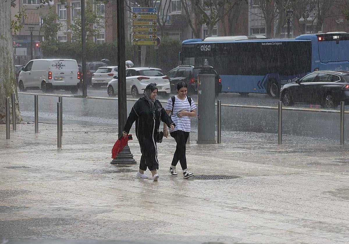 Dos viandantes caminan bajo la lluvia en Cartagena, en una foto de archivo.