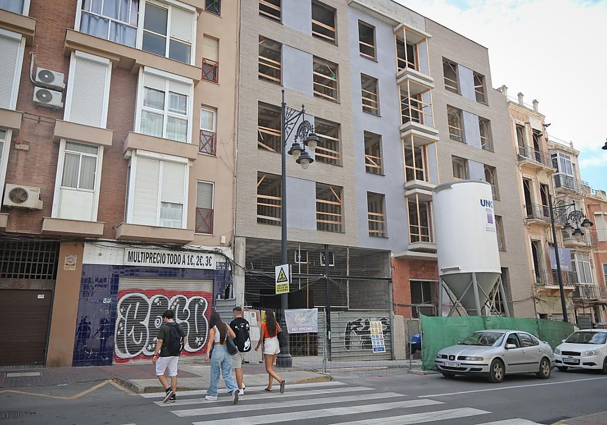 Cuatro jóvenes cruzan un paso de peatones junto al edificio que se dedicará a apartamentos turísticos en la calle San Diego.