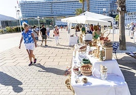 Una turista se queda mirando los bolsos y capazos de esparto en uno de los puestos.