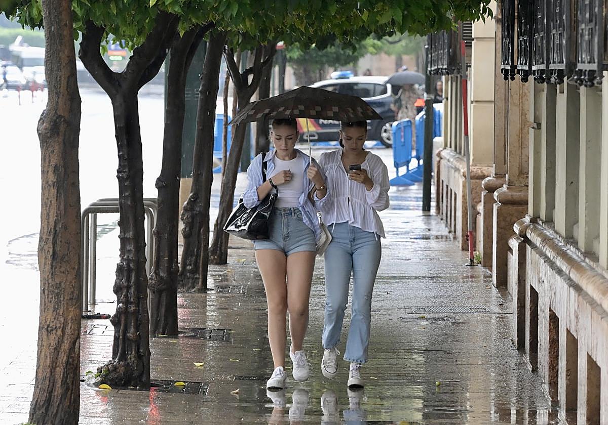 Dos jóvenes se protegen de la lluvia con un paraguas en Murcia, en una foto de archivo.